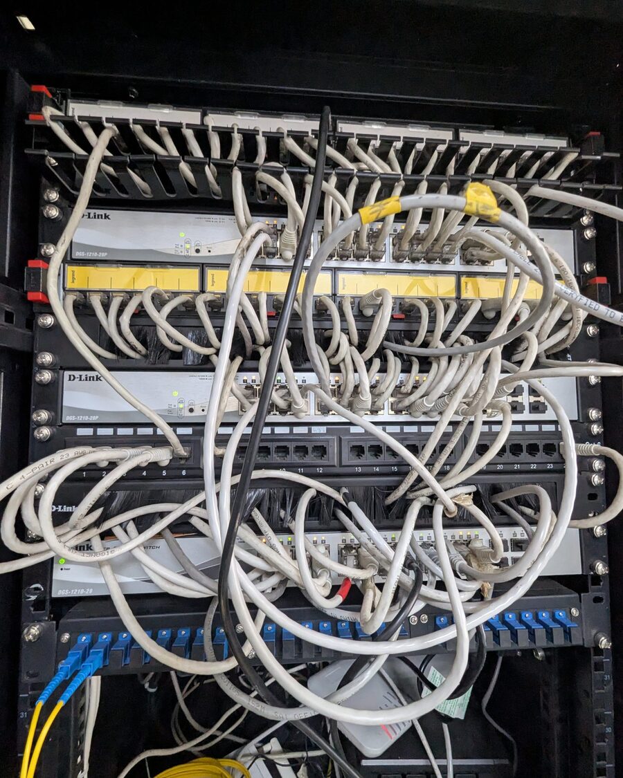 Netzwerkschrank mit ungeordnet verlegten Patchkabeln vor Switch und Patchfeld.